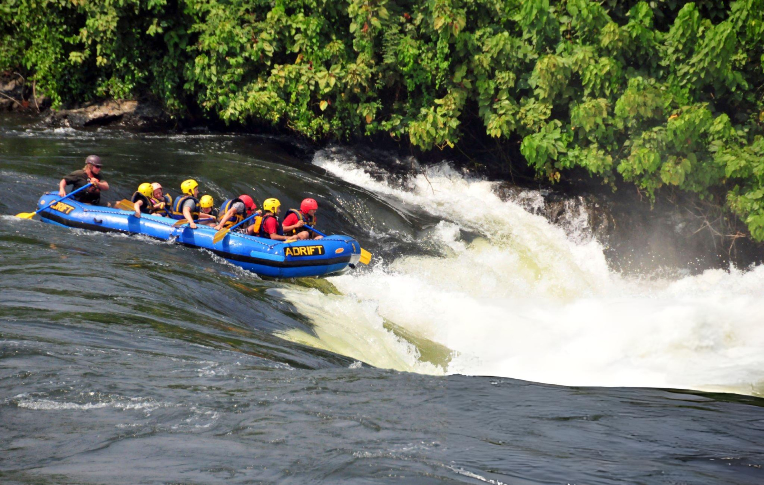 Traditional sailboat gliding across a broad river at soft golden light.